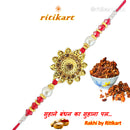 Decorative gold rakhi with red and white beads, a bowl of ladoo
